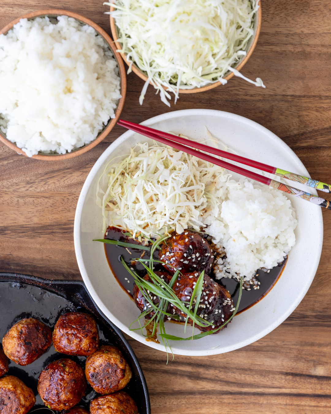 Japanese Chicken Meatballs (Tsukune) served with sushi rice and green cabbage, garnished with sesame seeds and spring onion