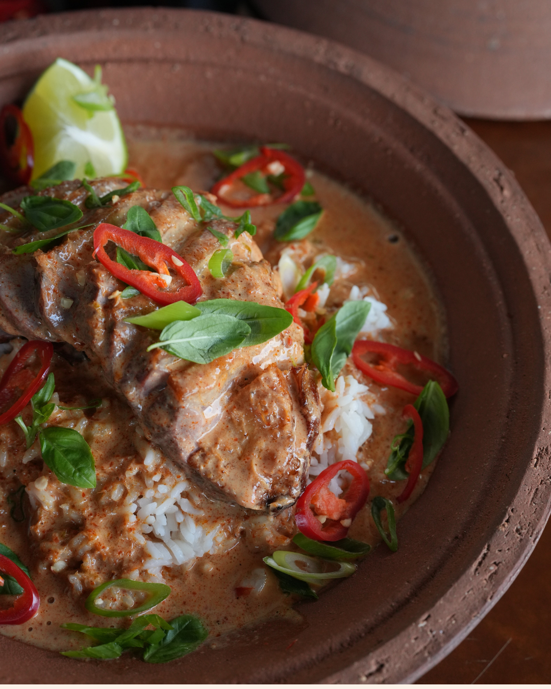 A rich and creamy Thai Red Duck Curry served over fluffy white rice, topped with fresh basil, red chilli, and a lime wedge.